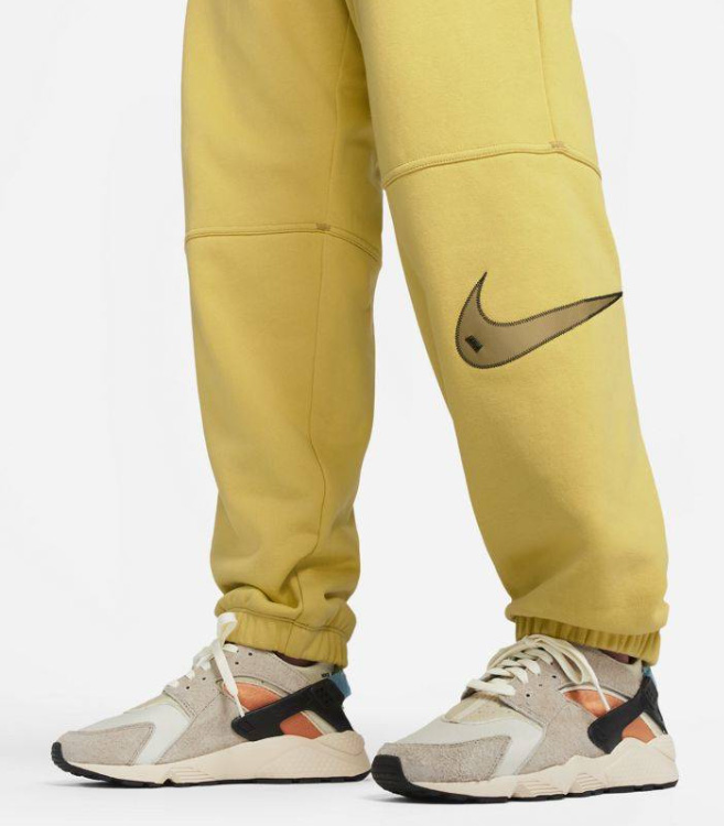 Boczny widok żółtych damskich spodni Nike Oversized Fit Swoosh High Rise DM6205-304 L z mankietami