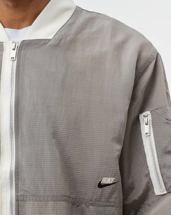 Boczny widok szarej męskiej kurtki Nike Bomber Jacket Sportswear Style Essentials DM6698-104 S z elastycznymi mankietami