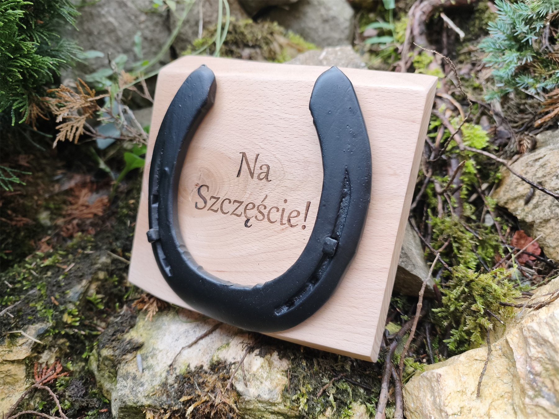 Bukowa deska z prawdziwą podkową i napisem Na Szczęście pokazana w naturalnej aranżacji