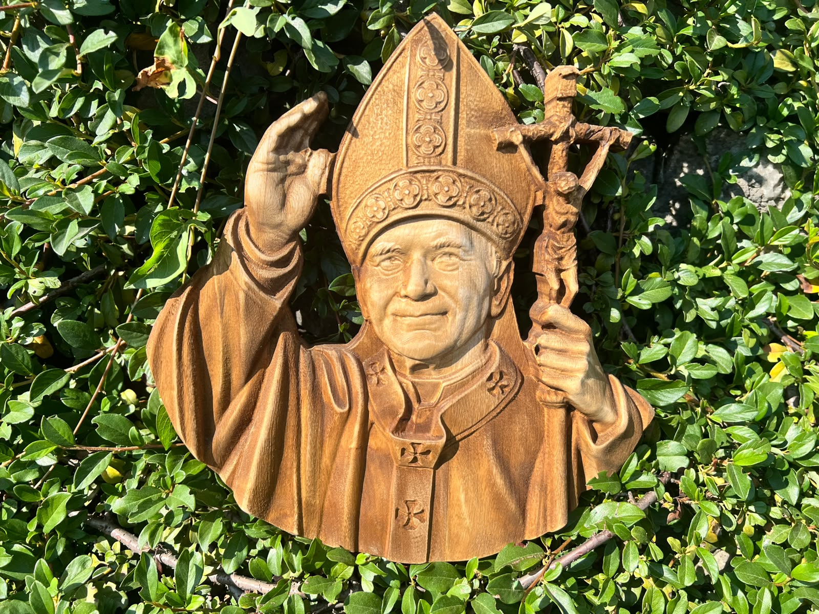 Zbliżenie twarzy, mitry i pastorału drewnianej płaskorzeźby Jana Pawła II