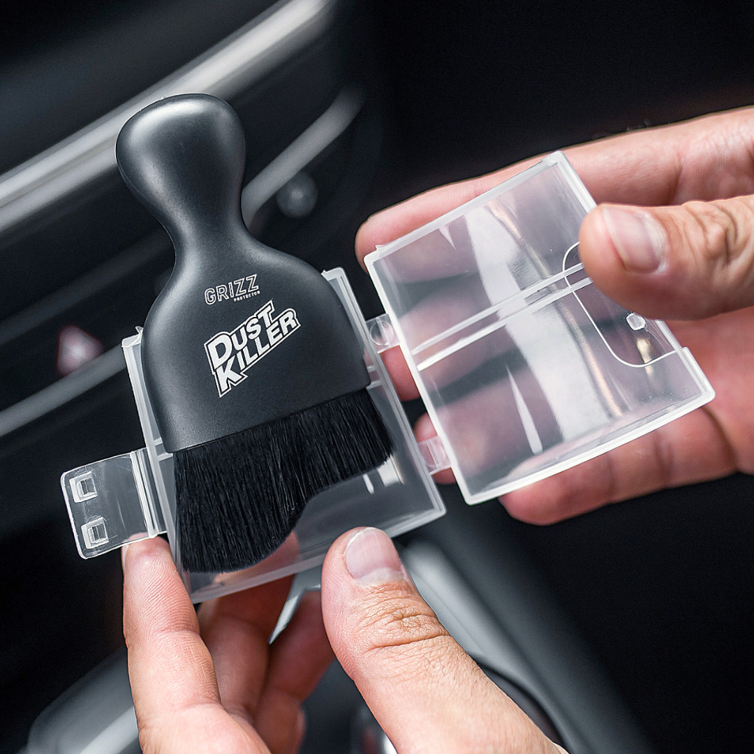 Someone holds a GrizzProtector Dust Killer Auto Detailbürste in a clear case, ideal for precise cleaning.