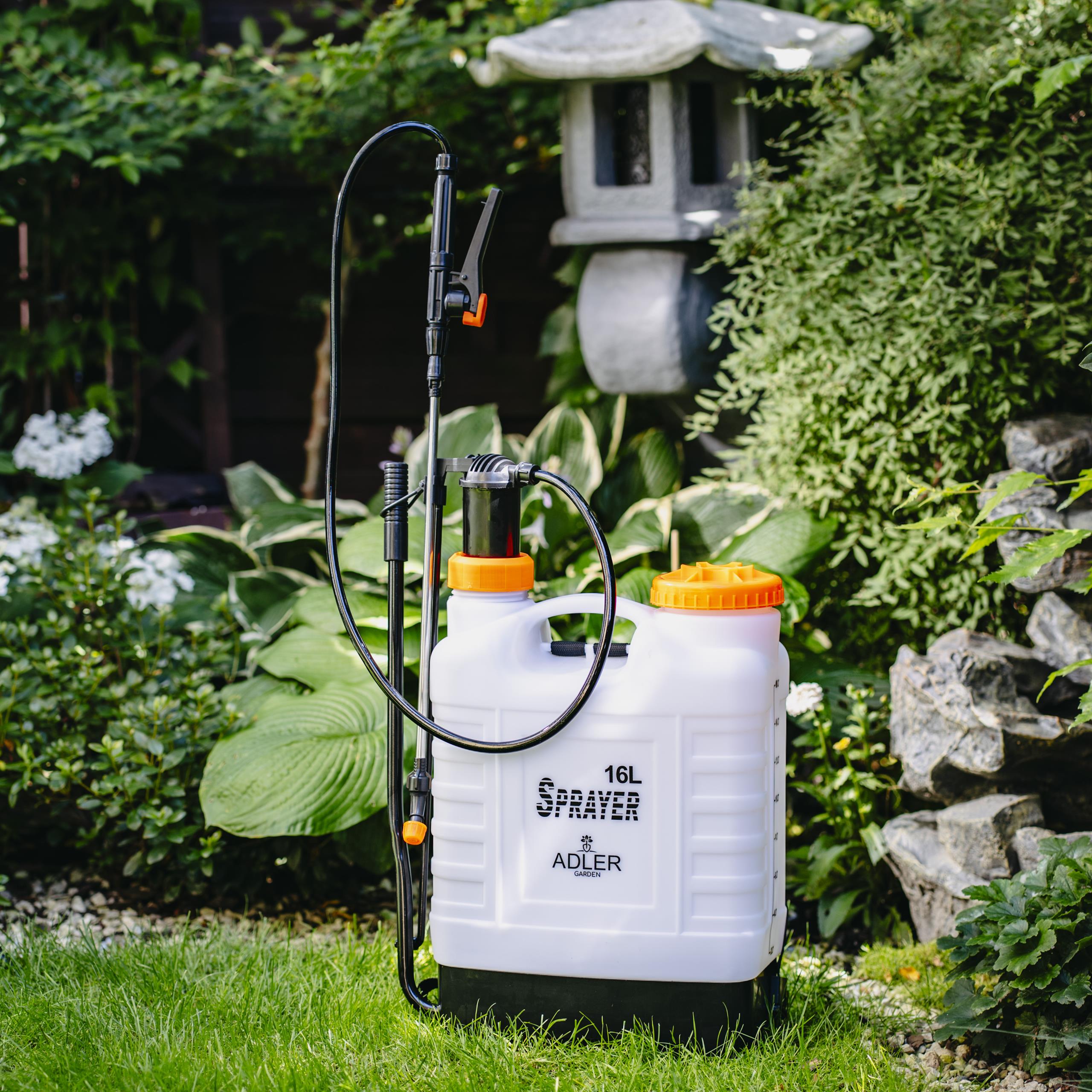 Składany chwytak manualny z obrotową głowicą i gumowymi szczękami, leżący obok narzędzi ogrodowych.